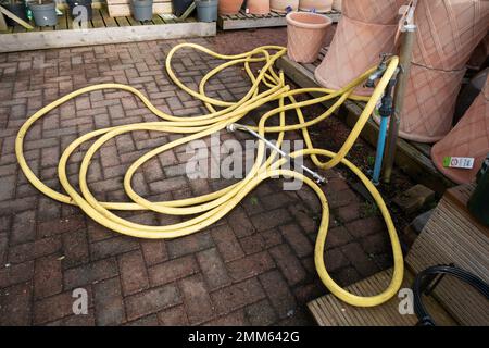 Un tubo da giardino di mercato con tubo flessibile giallo resistente all'attorcigliamento e dotato di ugelli di spruzzatura pratica distribuzione in un centro del giardino Foto Stock