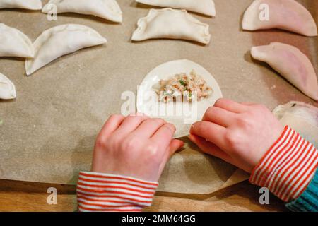 Primo piano del bambino piccolo che fa gnocchi cinesi a mano Foto Stock