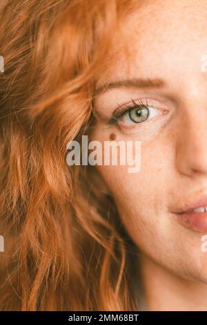 Chiusura di donna con capelli rossi e occhi verdi con un segno di bellezza Foto Stock