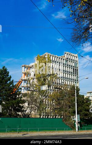 Demolizione del vecchio edificio con sloopkraan contro cielo nuvole blu. Foto Stock