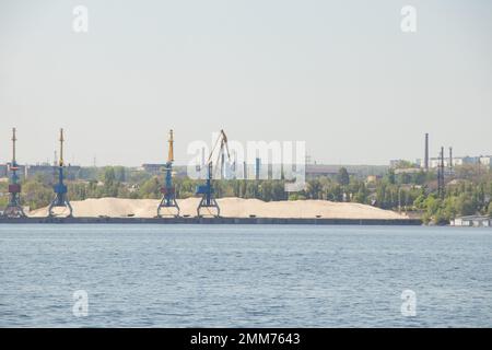 Gru sulle rive del con una montagna di sabbia sullo sfondo della città di Dnieper, caricando sabbia con gru Foto Stock