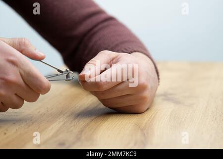 Primo piano delle mani maschili che tagliano le unghie. Giovane bell'uomo che si taglia le unghie delle dita Foto Stock