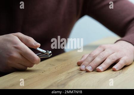 Primo piano delle mani maschili che tagliano le unghie. Giovane bell'uomo che si taglia le unghie delle dita Foto Stock