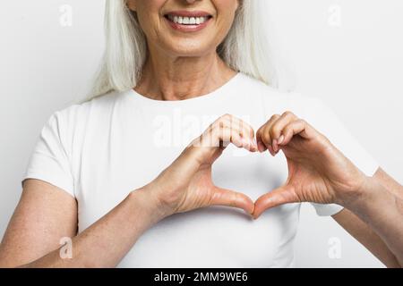 donna sorridente che mostra il cuore con le mani. Risoluzione e foto di alta qualità Foto Stock