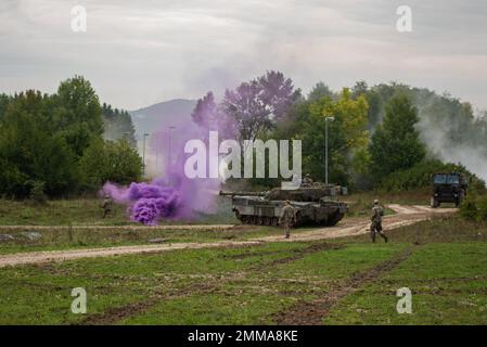 Soldati italiani con 4th reggimento carri armati, la Brigata Garibaldi ingaggia le forze opposte con un carro armato Ariete C1 mentre conduce un raid accanto ai paracadutisti dell'esercito degli Stati Uniti assegnati a 2nd battaglione, 503rd reggimento di fanteria paracadute al Joint Multinational Readiness Center di Hohenfels, Germania come parte dell'esercizio Saber Junction 22, 16 settembre, 2022. Saber Junction 22 è un esercizio di rotazione multinazionale progettato per valutare la prontezza della Brigata aerea dell'esercito degli Stati Uniti 173rd ad eseguire operazioni terrestri unificate in un ambiente congiunto e combinato e per promuovere l'interoperabilità con più di 4.500 p. Foto Stock