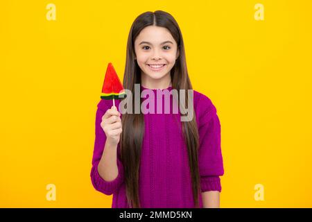 Bambino teen freddo con lollipop sopra sfondo isolato giallo. Dolce vita d'infanzia. Ragazza teen con caramella lollipop yummy. Foto Stock