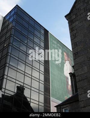 Il murale Nuart di Aberdeen incorniciato tra edifici moderni e vecchi contro un cielo blu Foto Stock