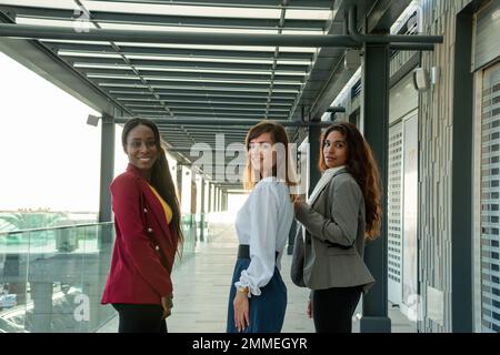 Tre giovani donne d'affari si rivolgono alla telecamera durante una riunione nel centro commerciale Foto Stock