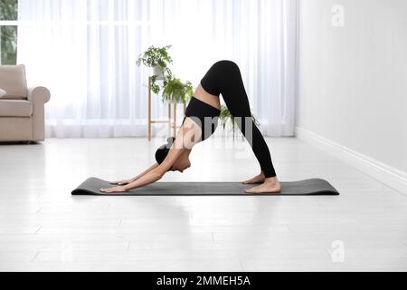 Giovane acrobata professionista che pratica lo yoga a casa Foto Stock