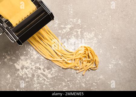 Macchina per pasta con pasta su tavolo grigio, vista dall'alto Foto Stock
