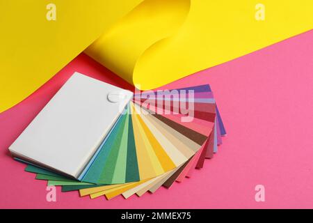 Tavolozza dei colori e carta gialla su sfondo rosa Foto Stock