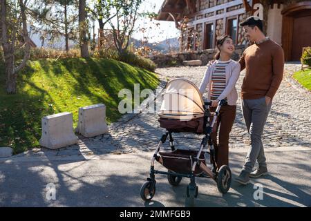 Una giovane coppia cammina spingendo un passeggino Foto Stock