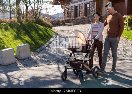Una giovane coppia cammina spingendo un passeggino Foto Stock