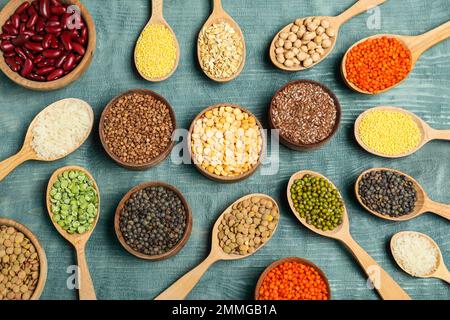 Composizione piatta con diversi tipi di legumi e cereali su tavola di legno blu. Grani organici Foto Stock
