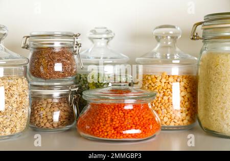 Diversi tipi di legumi e cereali in vasetti sulla tavola. Grani organici Foto Stock