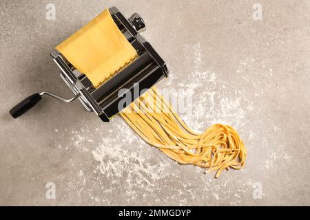 Macchina per pasta con pasta su tavolo grigio, vista dall'alto Foto Stock