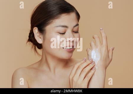 giovane donna con crema mani su sfondo beige. Foto Stock