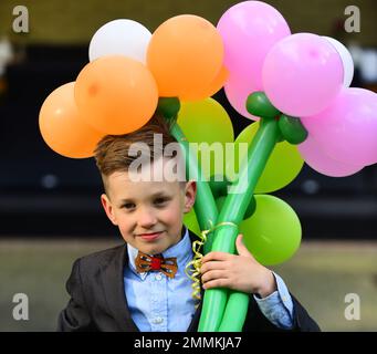 Scolaro con bouquet di fiori e palloncini. Va a scuola il 1 settembre. Nuovo anno accademico. Foto Stock