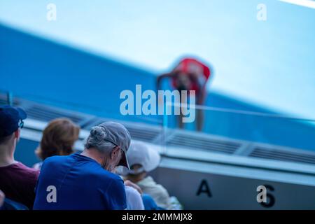 Folle che guardano una atleta professionista giocatore di tennis che gioca su un campo in un torneo di tennis in estate Foto Stock