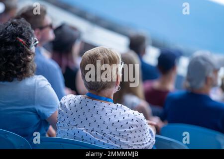 Folle che guardano una atleta professionista giocatore di tennis che gioca su un campo in un torneo di tennis in estate Foto Stock