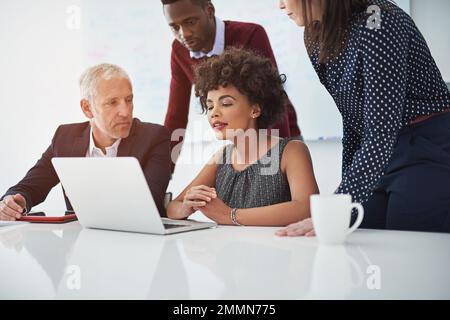 La concorrenza ci rende più veloci, la collaborazione ci rende migliori. un gruppo di uomini d'affari che discute qualcosa su un notebook. Foto Stock