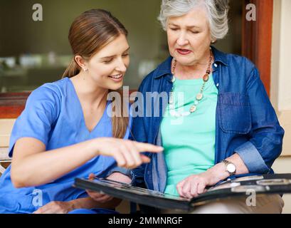 Passando attraverso l'album di famiglia. un residente e un'infermiera che guardano un album fotografico. Foto Stock