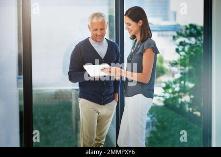 Ottenere una seconda opinione. due colleghi che hanno una conversazione su un tablet nel loro ufficio. Foto Stock