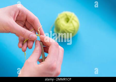 Mani uncinate in cotone e crochet su sfondo chiaro, fuoco selettivo, con spazio copia, fatte a mano. Foto Stock