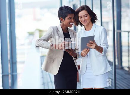 Condivisione di una nuova scoperta aziendale online. due giovani donne d'affari che utilizzano un tablet digitale insieme all'esterno di un ufficio. Foto Stock