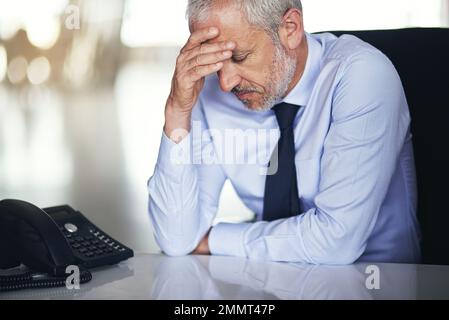 Im che ottiene troppo vecchio per questo... un uomo d'affari maturo che osserva sollecitato mentre lavora nel suo ufficio. Foto Stock