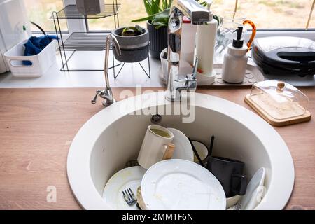 Piatti sporchi nel lavandino in cucina, pasticcio dopo pranzo, troppo pigri per lavare i piatti. Pulizia cucina, detersivo, servizi di pulizia Foto Stock