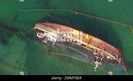 Vista aerea dall'alto della nave petroliera rotta rovesciata e arrugginita in acque poco profonde. Annegata nave dopo il relitto. Foto Stock