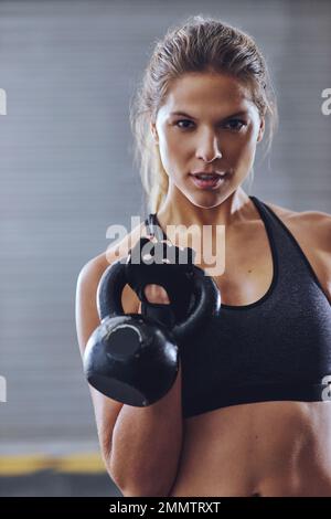 In questo per il fitness. una giovane donna che lavora con i kettlebells. Foto Stock