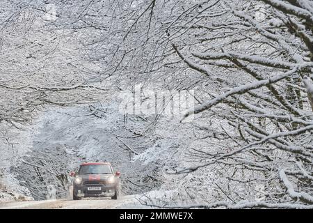 Un'auto viaggia attraverso la panoramica azienda vinicola Exmoor dopo una nevicata che attraversa la Gran Bretagna, Regno Unito Foto Stock