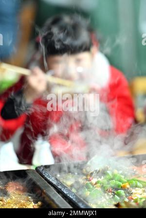 Enshi, Provincia cinese di Hubei. 29th Jan, 2023. Una ragazza gode di cibo locale in un punto panoramico nella Contea di Xuan'en, nella Provincia di Hubei della Cina centrale, 29 gennaio 2023. La contea di Xuan'en ha costruito sentieri, fontane e cabine per spuntini lungo il fiume Gongshui per aumentare l'economia notturna. Credit: Notizie dal vivo su Chen Xukai/Xinhua/Alamy Foto Stock