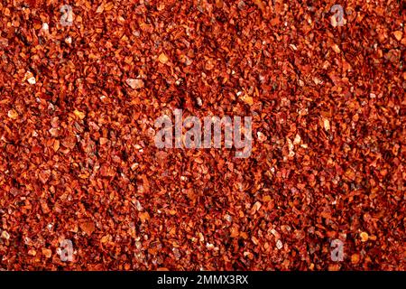 Scaglie di pepe rosso. Cumulo di peperoni schiacciati. Vista dall'alto dei peperoncini secchi. Primo piano Foto Stock