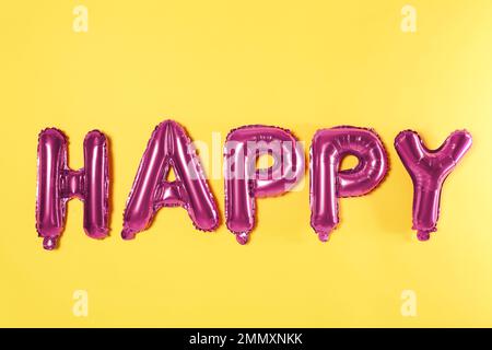 Parola FELICE fatto di palloncini rosa su sfondo giallo Foto Stock