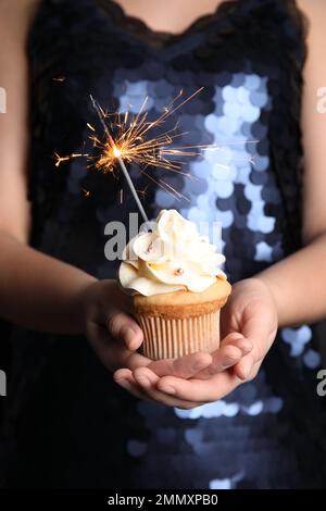 Donna che tiene cupcake di compleanno con scintilla, primo piano Foto Stock