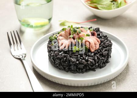 Delizioso risotto nero con pesce servito sul piatto Foto Stock
