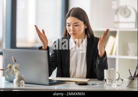 Giovane donna d'affari che lavora su un computer portatile in ufficio, bella donna d'affari asiatica sul posto di lavoro. Foto Stock