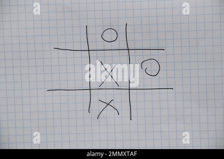 il gioco del tic-tac-toe è disegnato con una penna su un taccuino sbriciolato in una gabbia, gioco e riposo, gioco per bambini di tic-tac-toe Foto Stock