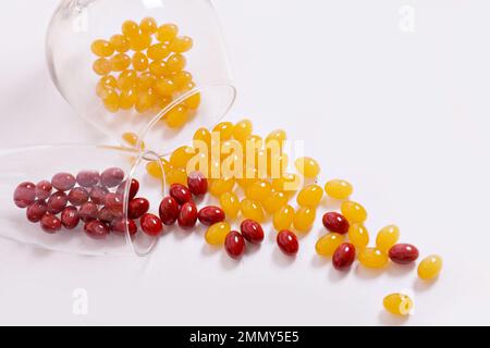 Compresse, capsule per la vista. Le vitamine rosse e gialle sono versate sulla tavola dal vetro. Lenti diottriche, miopia, lungimiranza. Corpo, cuore e ossa sani. Foto di alta qualità Foto Stock
