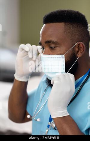 Medico afro-americano che lavora in ospedale, indossando una maschera facciale Foto Stock