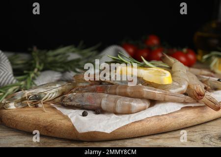 Gamberetti freschi crudi con fettina di limone e rosmarino su tavola di legno Foto Stock