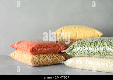 Diversi tipi di legumi e cereali su tavola in marmo grigio. Grani organici Foto Stock