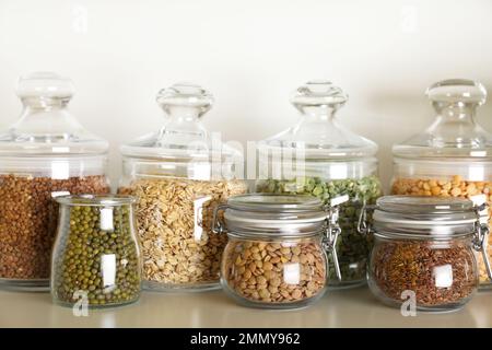 Diversi tipi di legumi e cereali in vasetti sulla tavola. Grani organici Foto Stock