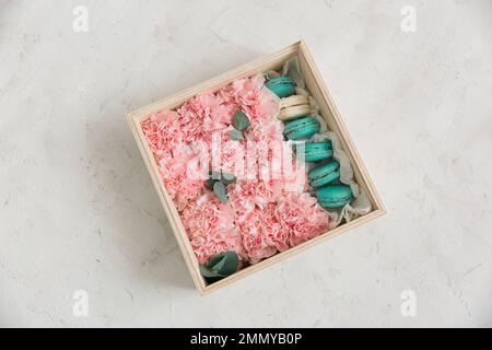 Garofani e macaron rosa in scatola di legno. NATURA MORTA ROSA ROSA BLUSH Foto Stock