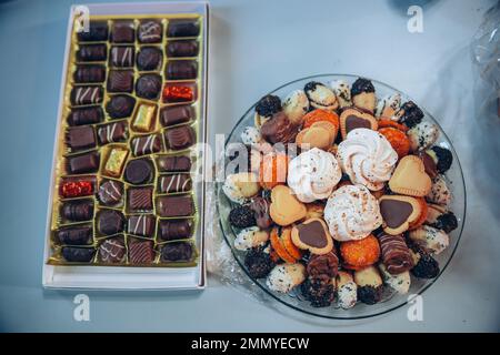 Scatola e piatto con caramelle e biscotti diversi allestiti per gli ospiti in vacanza. Foto di alta qualità Foto Stock