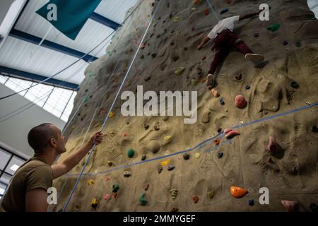 U.S. Air Force Senior Airman Brenden Pellerin, 319th Reconnaissance Wing centro fitness augmentee, belays come staff Sgt. Jesus Benitez, 319th ufficiale non commissionato del gruppo medico responsabile del laboratorio odontoiatrico, mentre si arrampica sulla parete rocciosa 23 settembre 2022, nel centro fitness sulla base dell'aeronautica di Grand Forks, North Dakota. I tecnici del centro fitness ricevono corsi di formazione e certificazioni per il funzionamento sicuro della parete rocciosa. Foto Stock