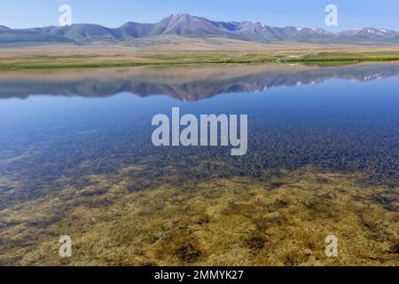 Montagne che si riflettono in un lago lungo la catena montuosa di AT-Bashy, la regione di Naryn, il Kirghizistan Foto Stock